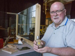 Dave Pulsifer, the vintage camera consultant for the ‘Snapshot in Time’ exhibit, has collected hundreds of cameras since grade school and many of these rare and original pieces are included in the displays. Here he holds a bottle of ‘Flash Powder’ that sometimes caused lethal explosions when used to illuminate photos in the 1890s. photos by Isobel Harry.
