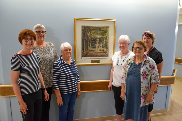 Manor Auxiliary members hang painting honouring late volunteer