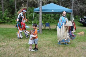 Julia and Noodin pause for a hug during an intertribal at the Sheshegwaning traditional powwow Saturday much to the delight of the dancers around them.