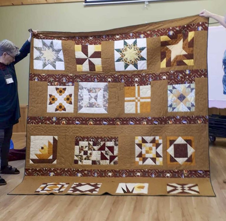 Happy Quilters present quilt to man who lost home to fire